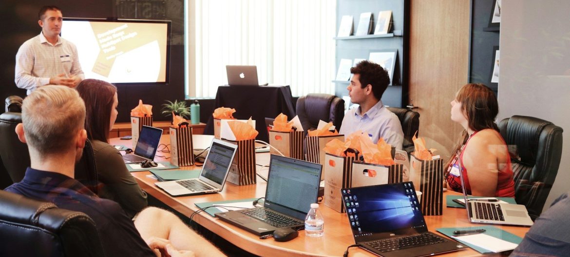 man standing in front of people sitting beside table with laptop computers