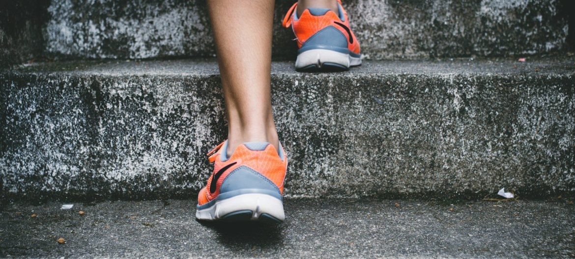 person wearing orange and gray Nike shoes walking on gray concrete stairs
