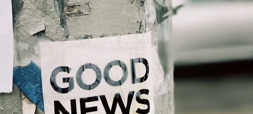 Photo by Jon Tyson white Good News Is Coming paper on wall